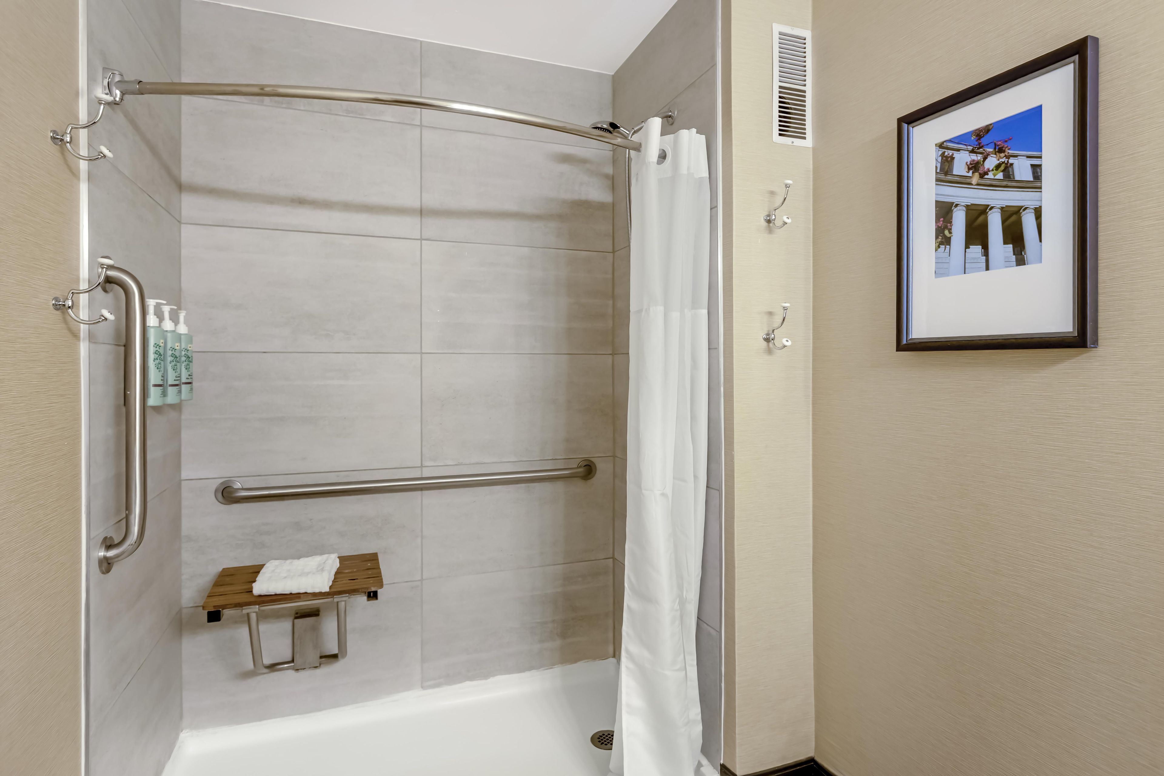 A shower area with a glass door, a towel rack, and a framed picture on the wall.