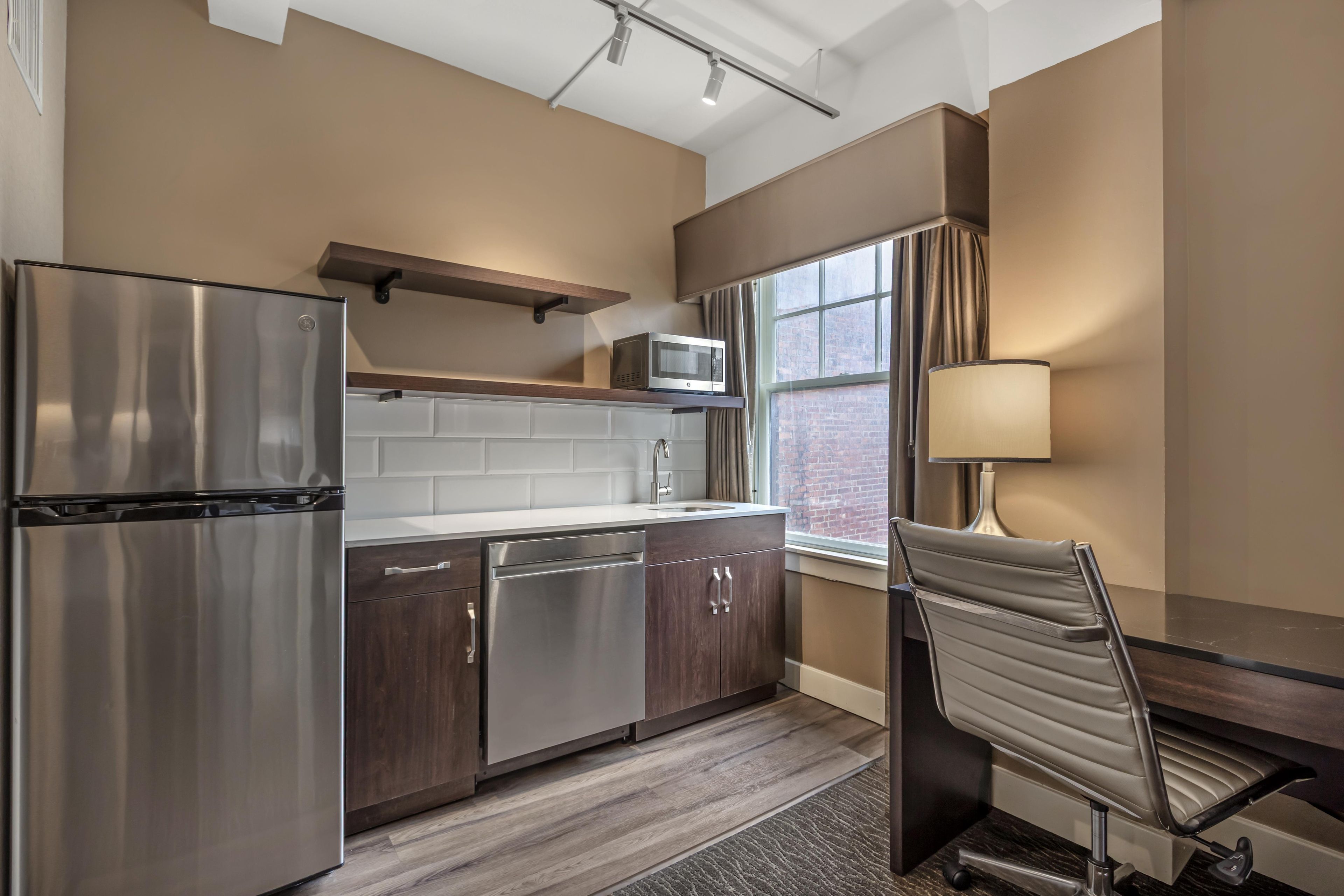 A modern kitchen with stainless steel appliances, a microwave, and a window with curtains.