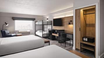 Ein modernes Hotelzimmer mit Stockbetten, einem Schreibtisch, einem Stuhl, einem Fernseher und einem Kleiderschrank.