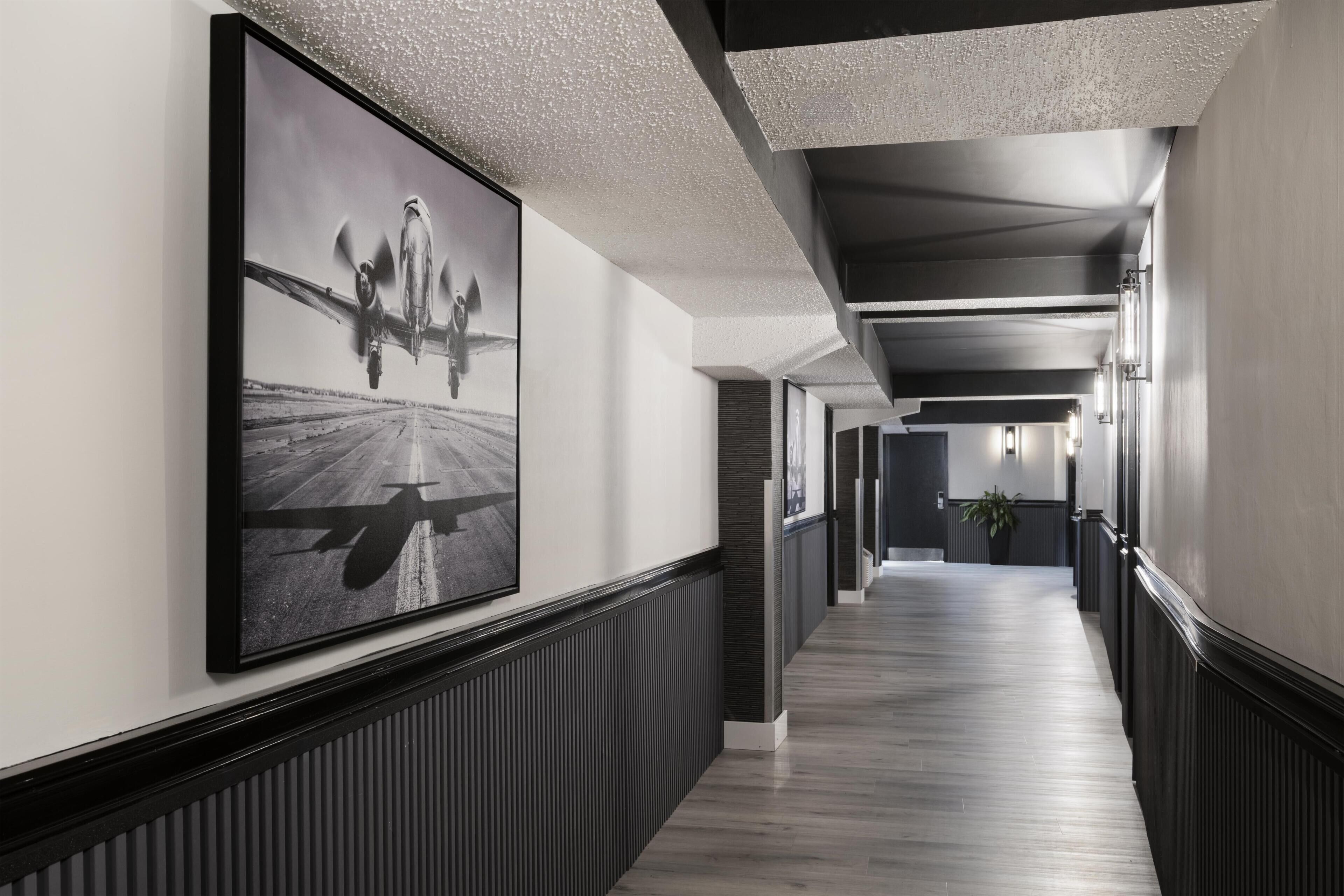 A hallway with a large black and white airplane photograph on the wall, a wooden floor, and a modern ceiling design.