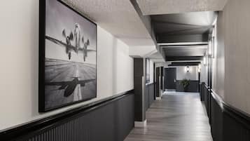 A hallway with a large black and white airplane photograph on the wall, a wooden floor, and a modern ceiling design.