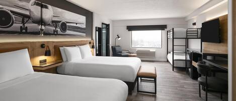 A hotel room with two beds, a desk, a chair, a TV, and a large window.