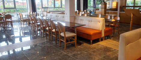 A spacious restaurant with high ceilings, large windows, and a mix of seating including tables and booths.