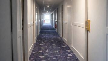 A long, narrow hallway with a floral carpet, white walls, and doors on both sides.