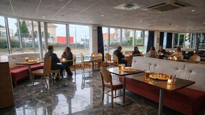 Un restaurante moderno con suelos de mármol, mobiliario de madera y grandes ventanales que ofrecen vistas al exterior.