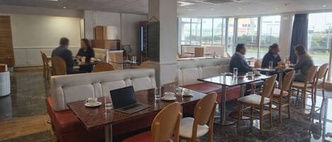 A modern dining area with booths and tables, large windows, and a view of the outside.