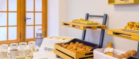 A breakfast buffet with pastries, bread, and coffee.