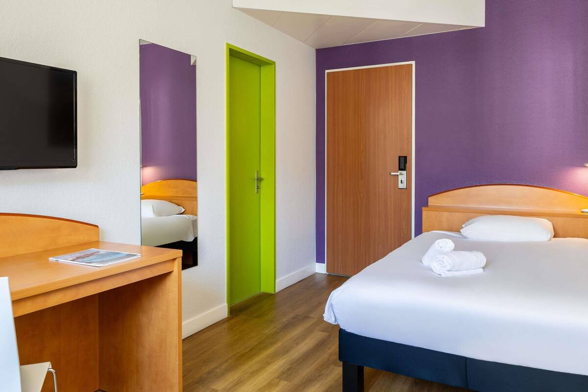Una habitación de hotel con cama, escritorio y televisor.