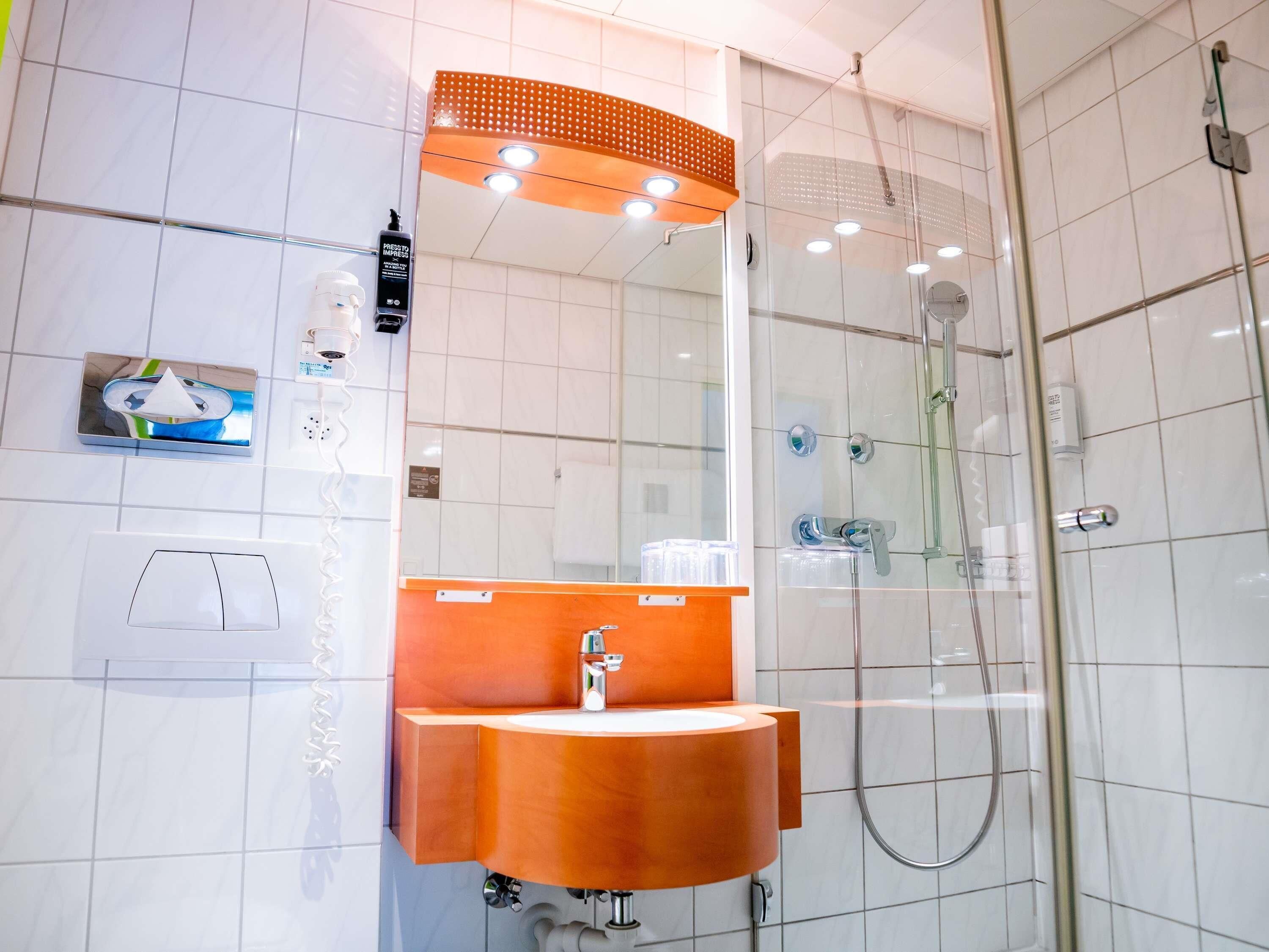 A modern bathroom with a glass-enclosed shower, a sink with a wooden countertop, and a mirror above the sink.