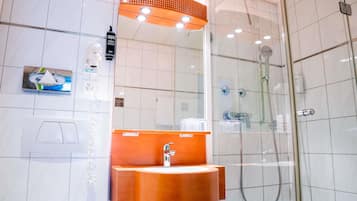 Un bagno moderno con doccia vetrata, lavabo con piano in legno e specchio sopra.