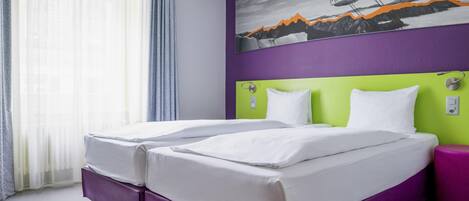 Ein Hotelzimmer mit zwei Betten, einem violetten Kopfteil, einem Gemälde einer Berglandschaft und einem Fenster mit transparenten Vorhängen.