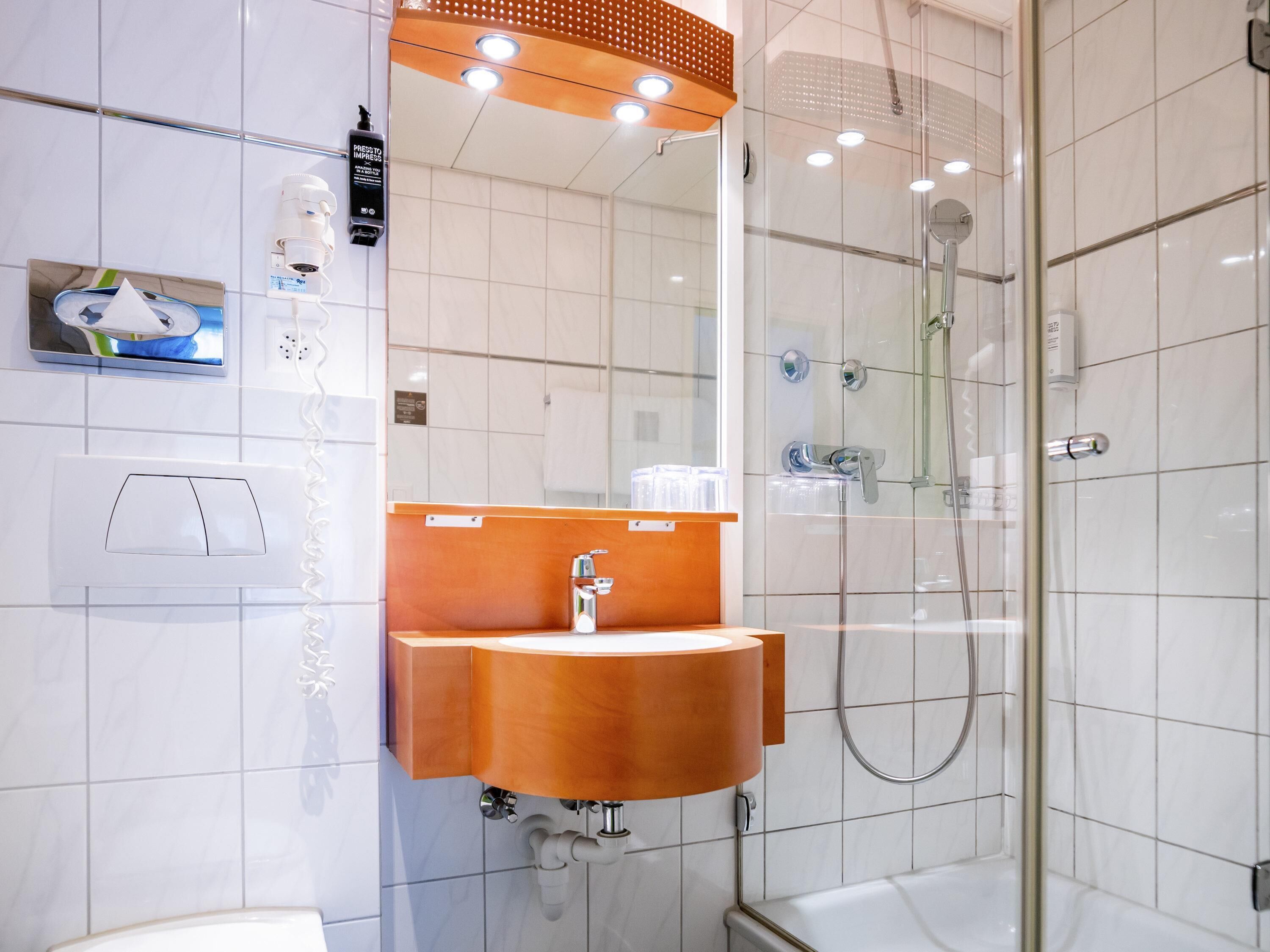 A modern bathroom with a glass-enclosed shower, a wooden vanity, and a large mirror.