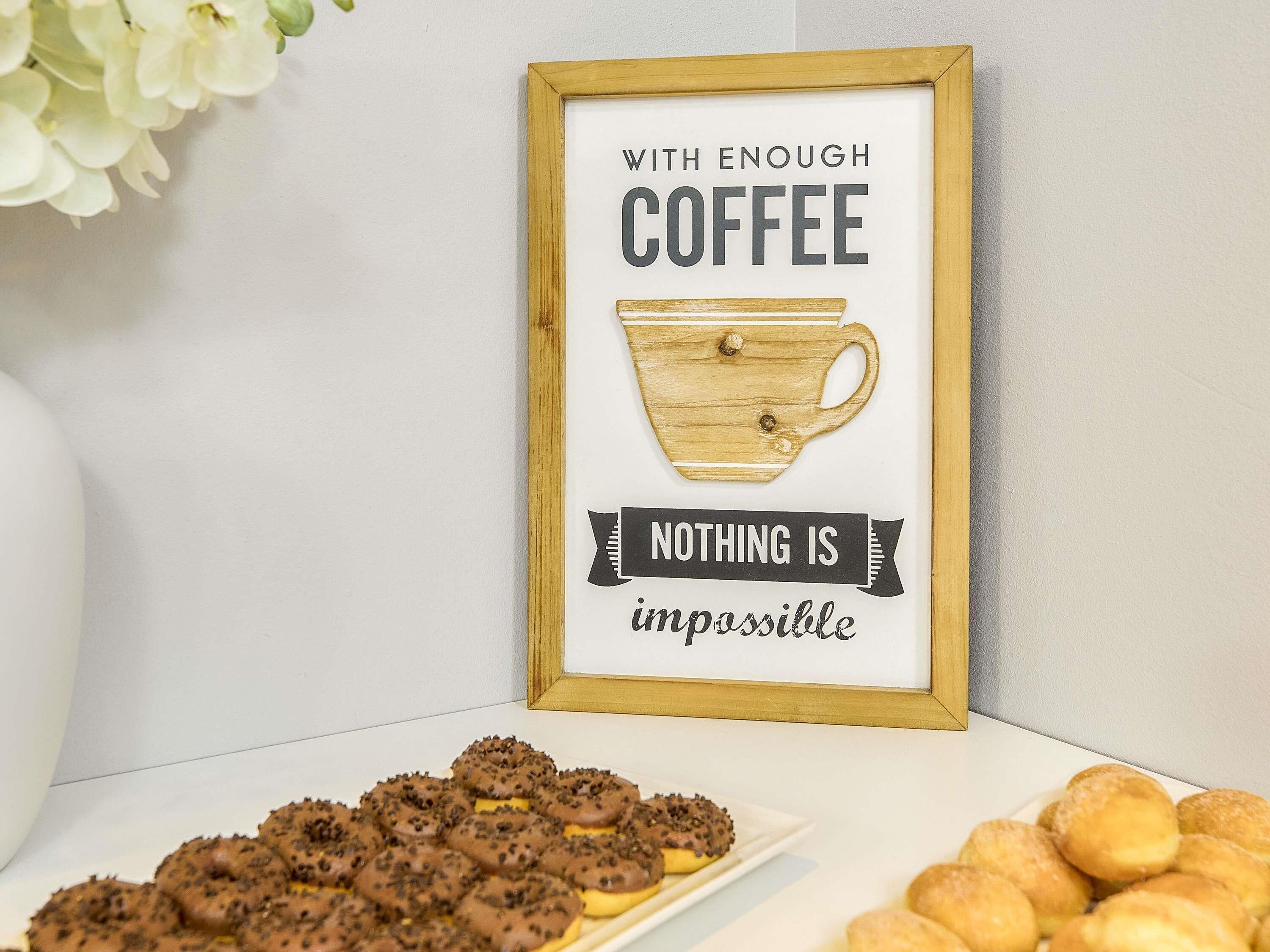A framed inspirational quote with a coffee cup illustration, a plate of chocolate-covered cookies, and a plate of plain cookies.