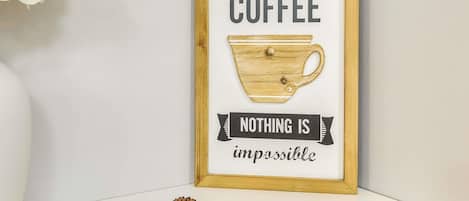 A framed inspirational quote with a coffee cup illustration, a plate of chocolate-covered cookies, and a plate of plain cookies.