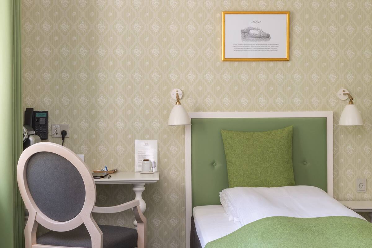 Habitación de hotel con cama, escritorio, silla y un cuadro en la pared.