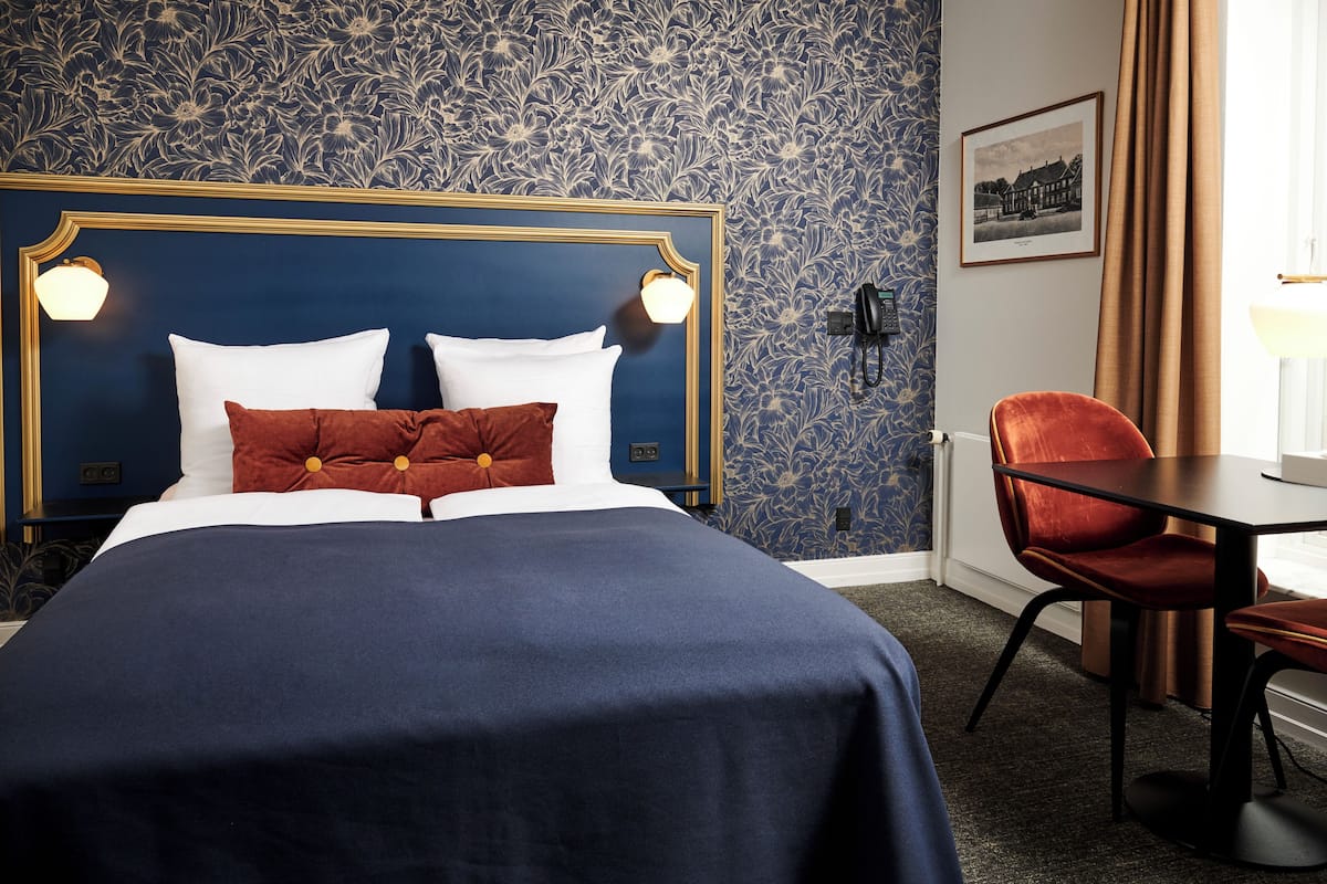 Una habitación de hotel con una cama grande, un escritorio y una silla.
