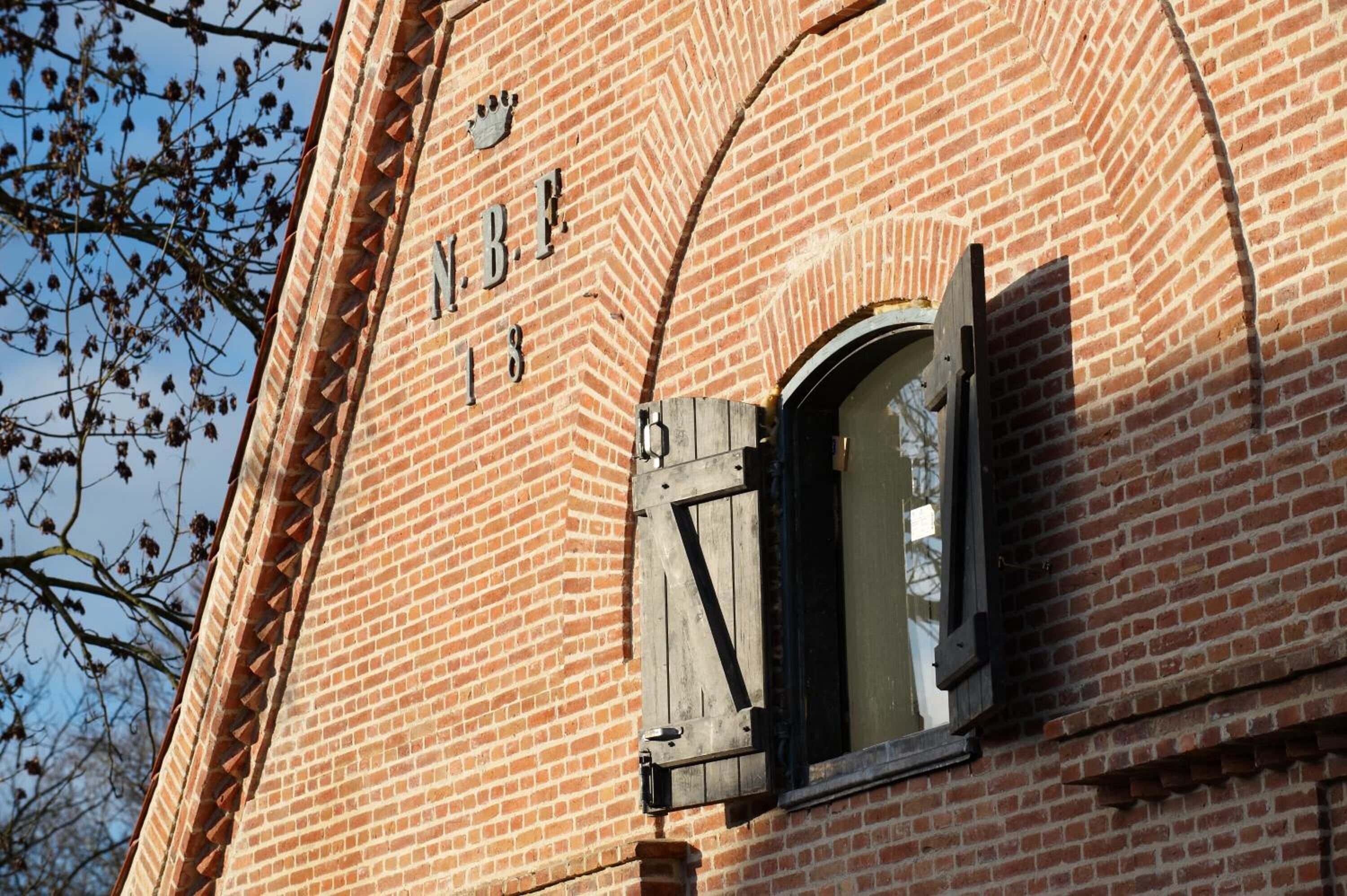 Edifici de maó amb una finestra i la inscripció "J.B.E. 18".