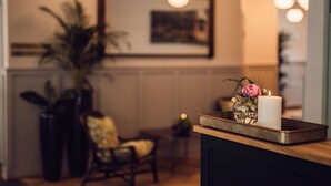 A cozy interior with a wooden counter, a white candle, and a vase with flowers. - Arnbjerg Pavillonen (Varde)