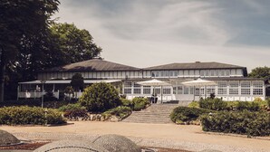 A building with a symmetrical facade, large windows, and a central staircase leading to the entrance. - Arnbjerg Pavillonen (Varde)