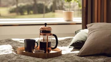 Un dormitorio acogedor con cama, cafetera, taza y bandeja.