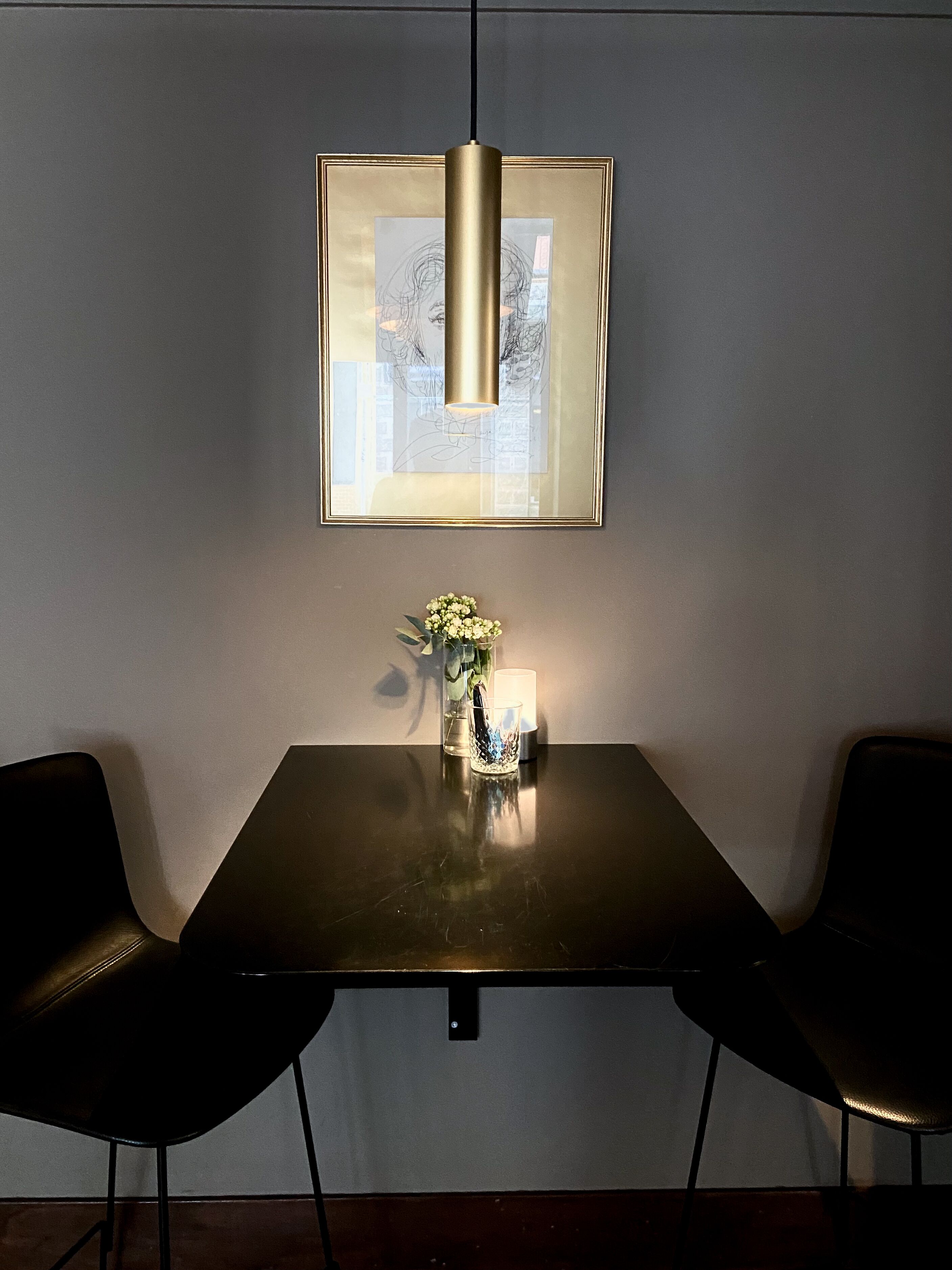 Een donkerhouten tafel met een bloevas en een lijst met een foto erboven.