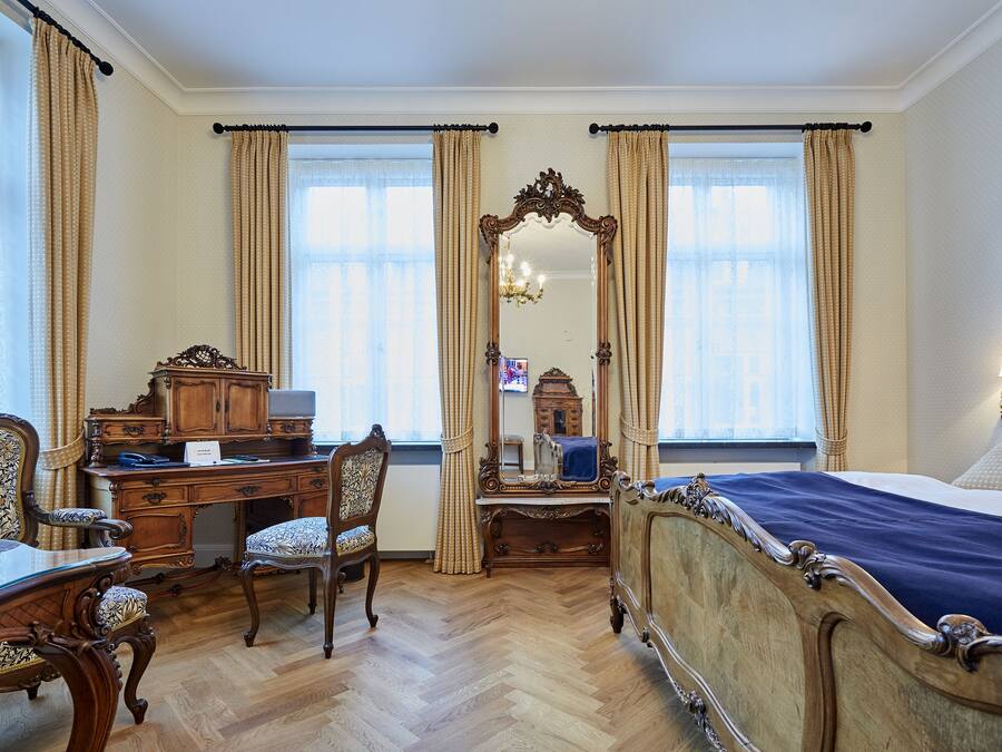 Quarto clássico com cama de madeira, escrivaninha, cadeira e espelho.