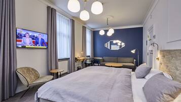 Habitació d'hotel moderna amb un llit gran, escriptori, cadira, televisió i mirall.