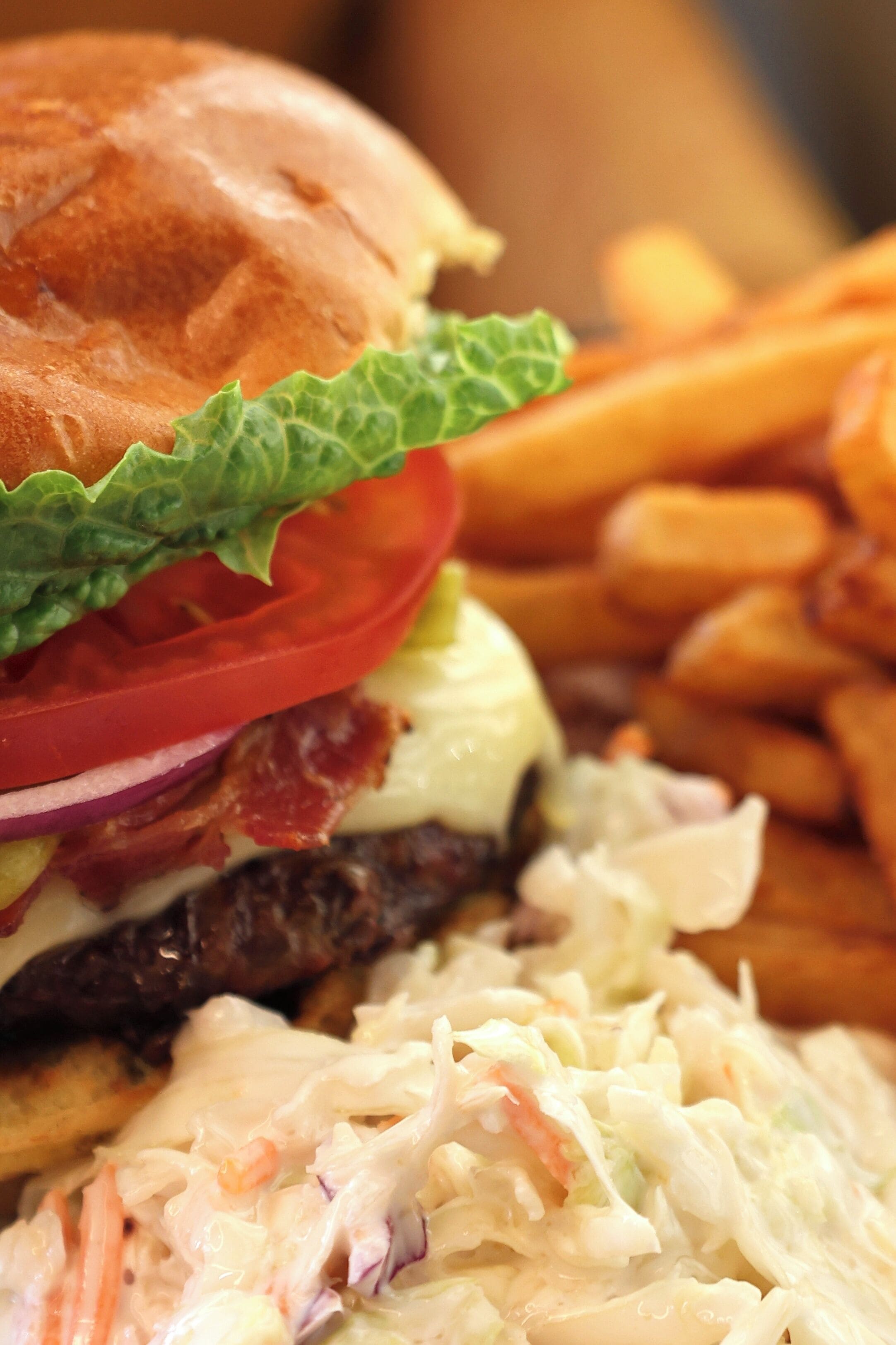 Ein Burger mit Salat, Tomate und Zwiebeln, dazu Pommes und Krautsalat.