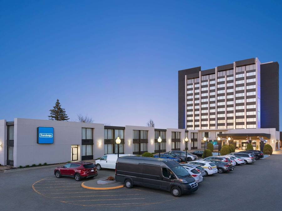 Un hotel Travelodge con un estacionamiento, una furgoneta y varios coches aparcados al frente.