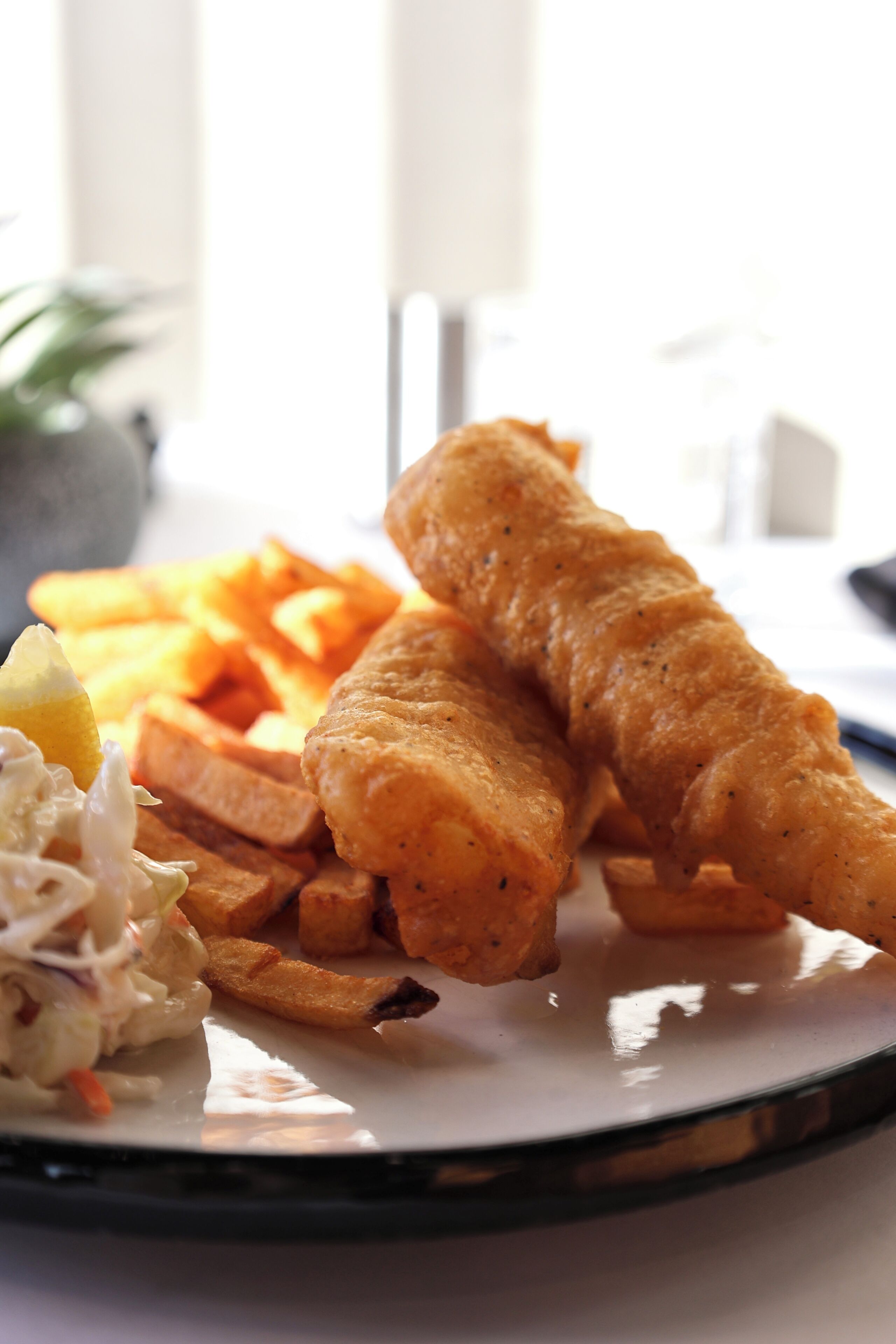 A plate with fish and chips, a side salad, and a lemon wedge.