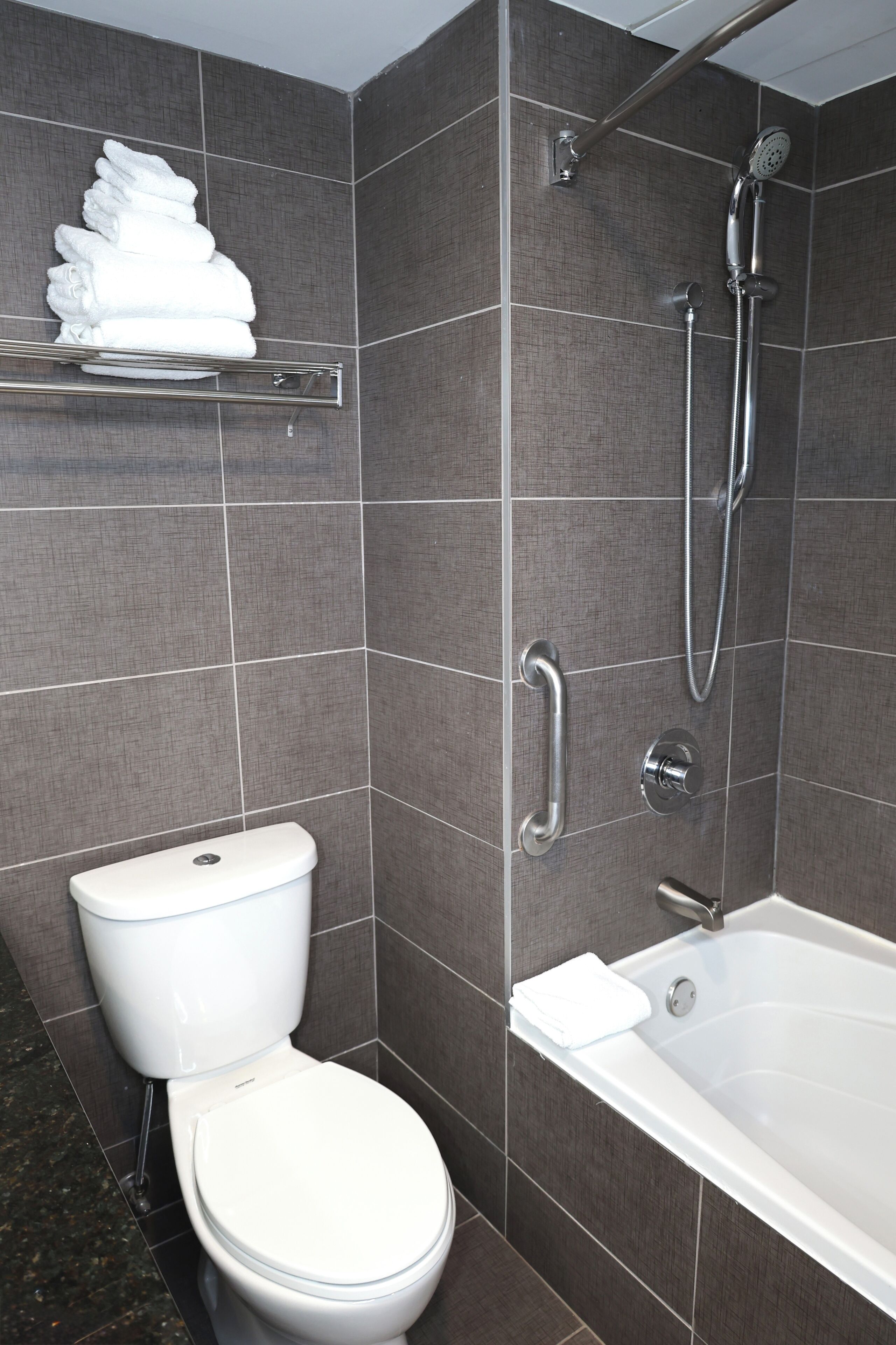 Un baño con inodoro, ducha con cabezal de ducha manual y bañera.