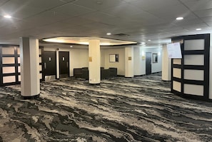 A conference room with a patterned carpet, white pillars, and black-framed doors. - Travelodge by Wyndham Hotel & Convention Centre Quebec City (Québec City)