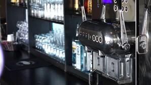 A bar area with shelves stocked with various liquor bottles and a coffee machine. - Travelodge by Wyndham Hotel & Convention Centre Quebec City (Québec City)