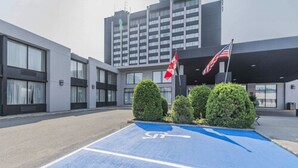 A parking area with a wheelchair symbol, a building entrance, and two flags. - Travelodge by Wyndham Hotel & Convention Centre Quebec City (Québec City)