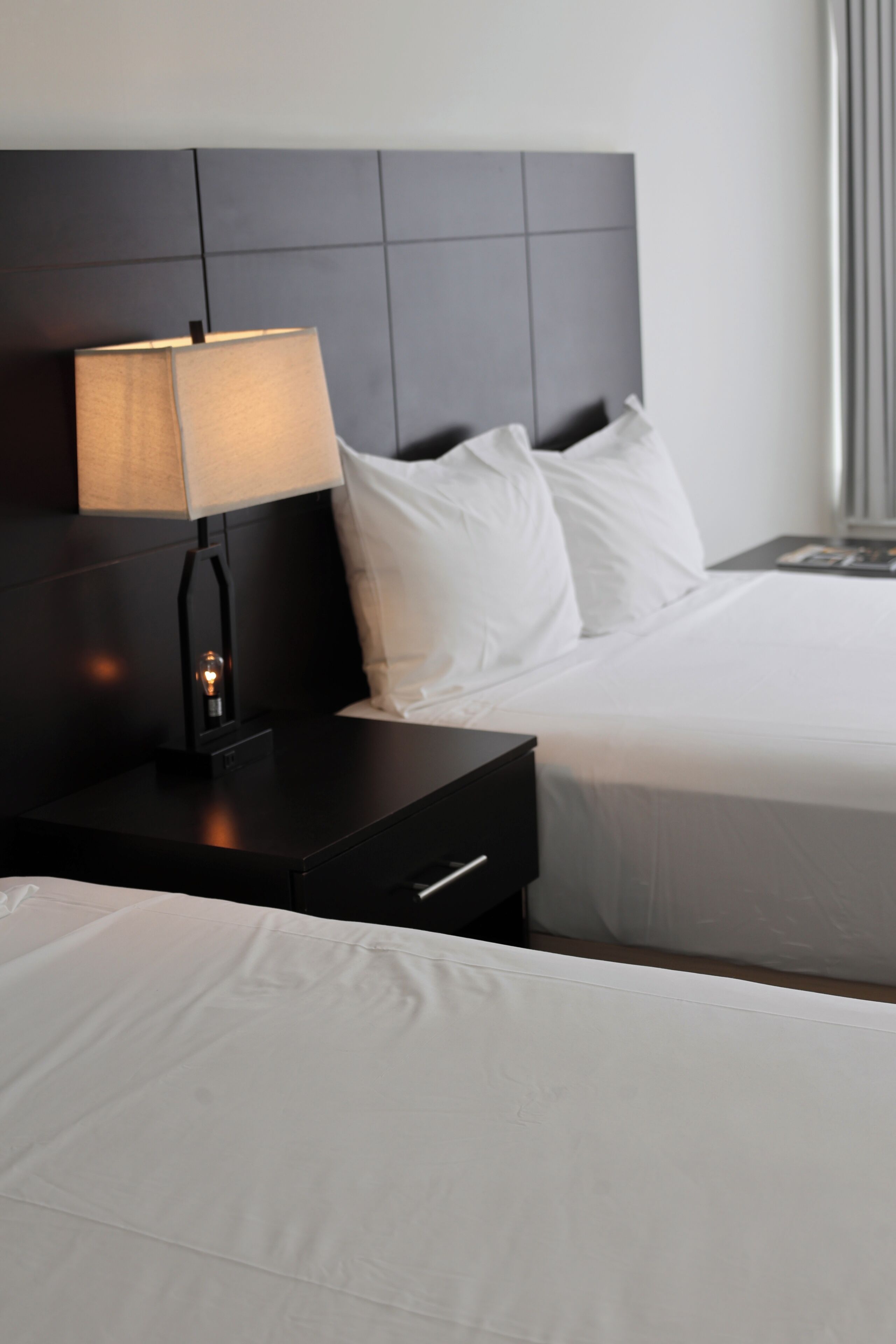 A hotel room with a bed, a nightstand with a lamp, and a headboard.