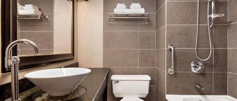 A modern bathroom with a vessel sink, toilet, shower, and a bathtub.