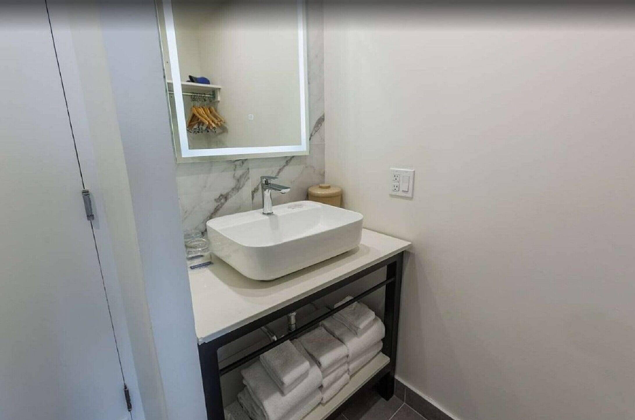 A bathroom with a white sink, a mirror, a towel rack, and a toilet.