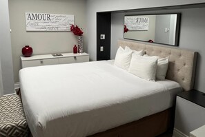 A bedroom with a large bed, a bedside table, a dresser, a mirror, and a wall with text. - Travelodge by Wyndham Hotel & Convention Centre Quebec City (Québec City)