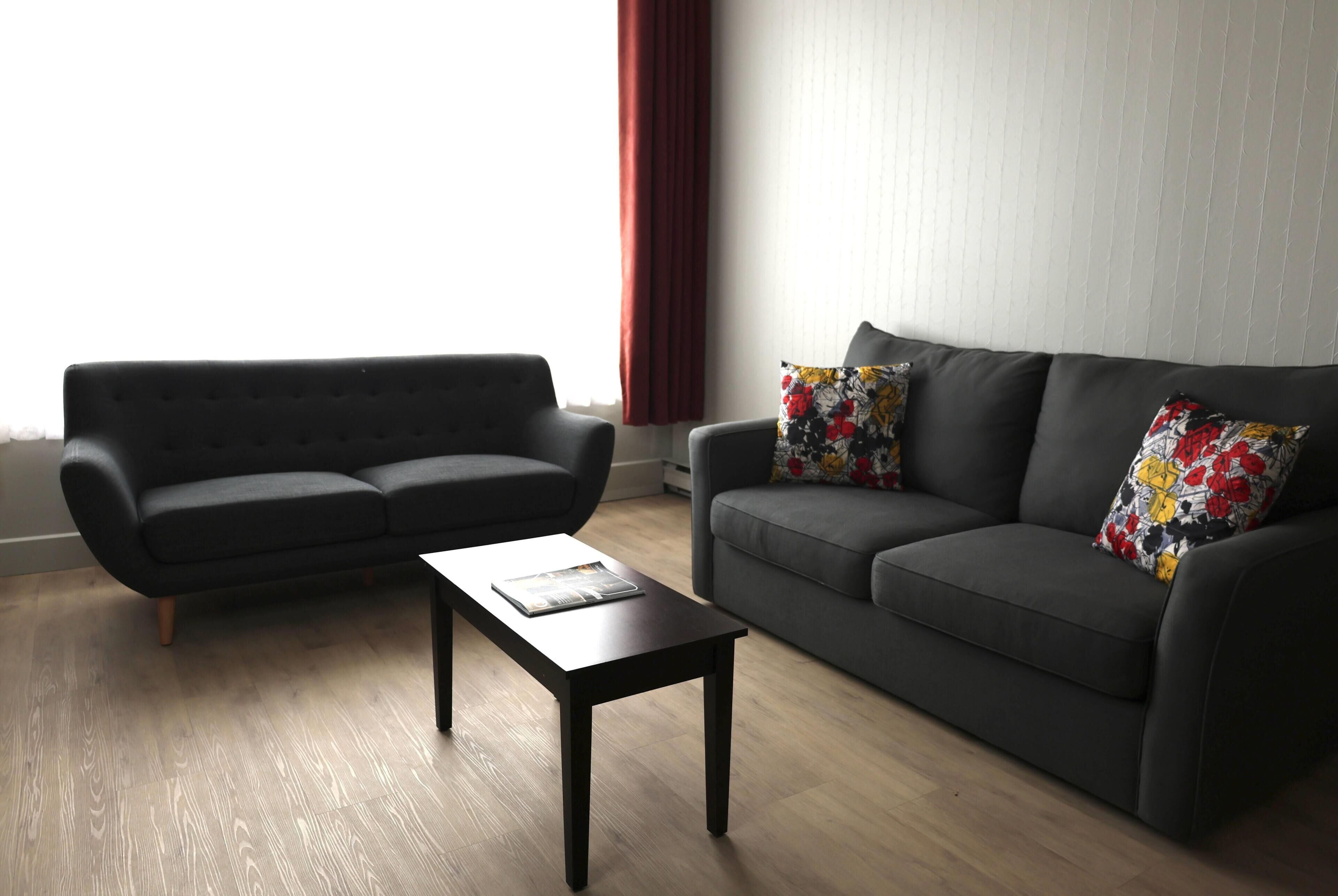Una sala de estar con un sofá, una mesa de centro y una ventana con cortinas.