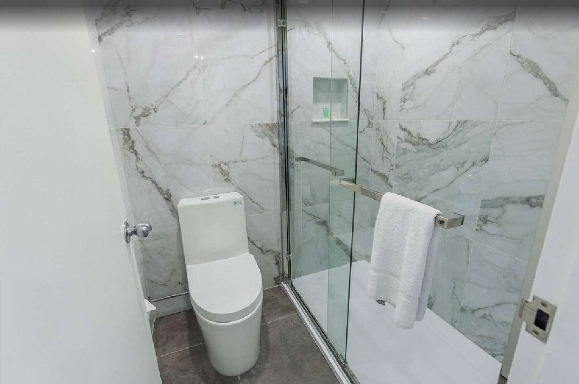 Un baño moderno con cabina de ducha de vidrio, inodoro y perchero para toallas.