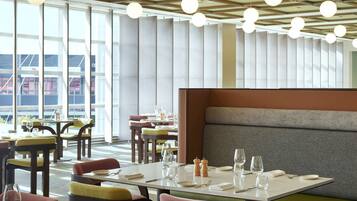 A modern restaurant interior with high ceilings, round pendant lighting, and a mix of seating options including tables and booths.