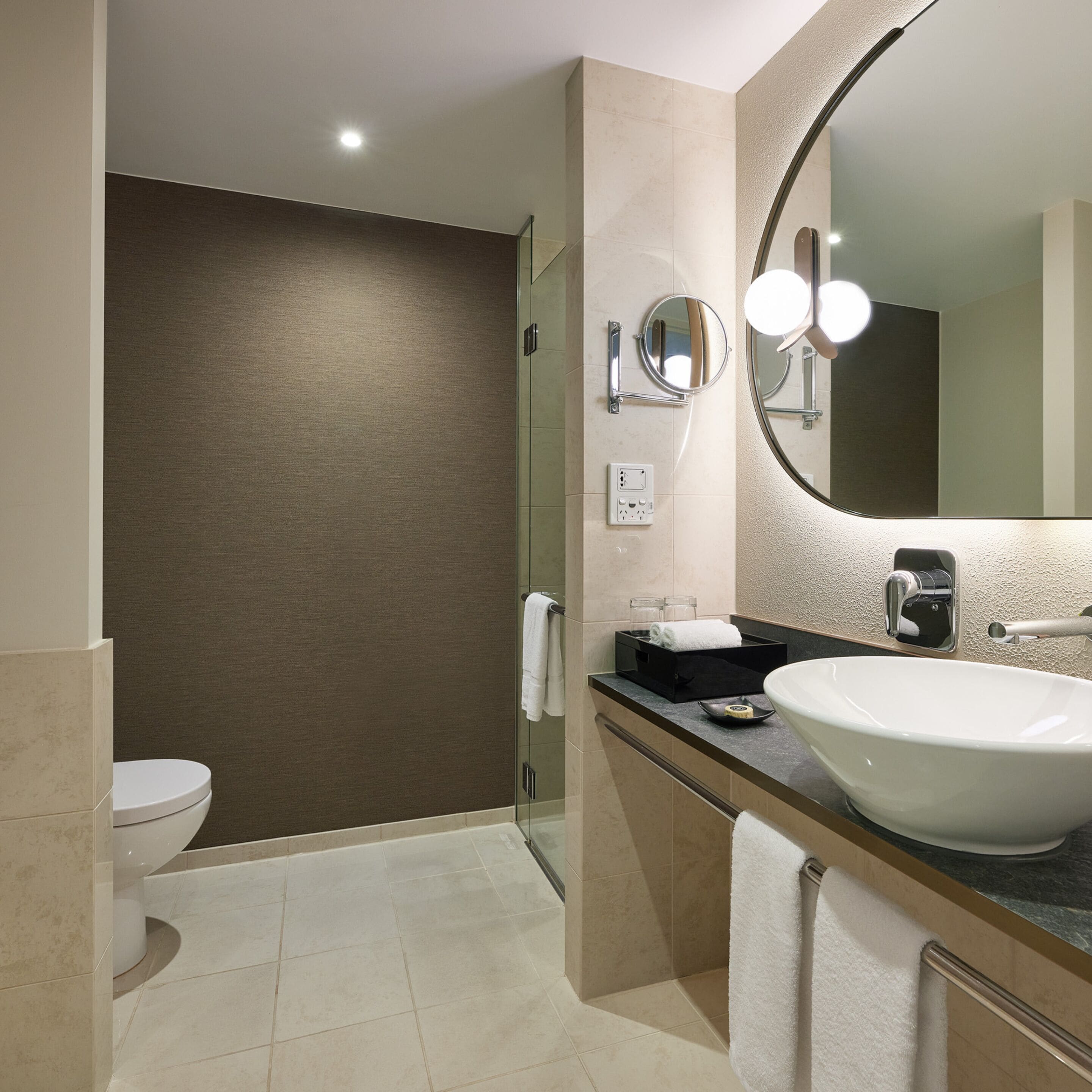 A modern bathroom with a large sink, a mirror, and a toilet.