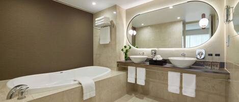 A modern bathroom with a bathtub, two sinks, and a large mirror.