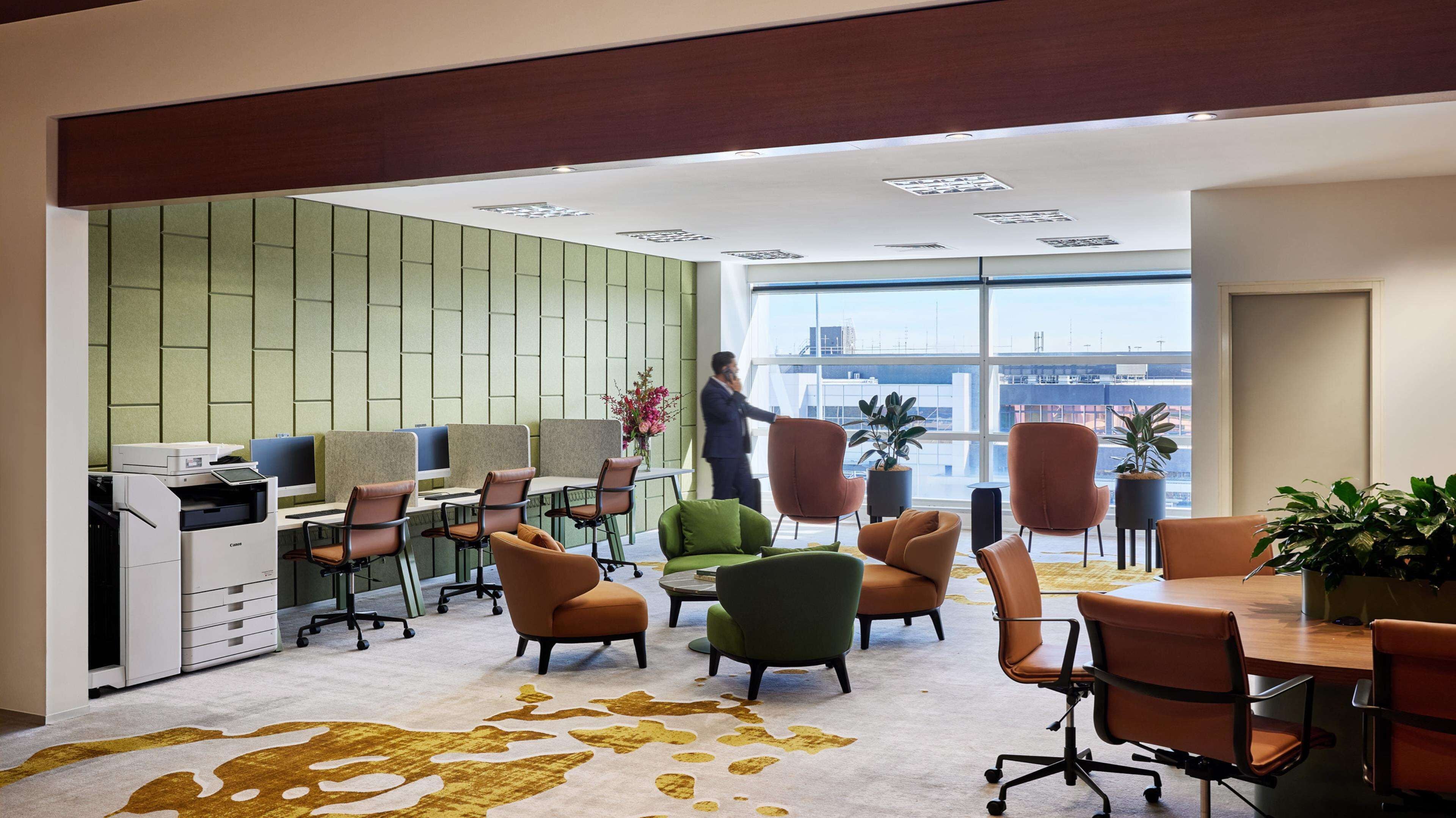 Un espace de bureau moderne, doté de cloisons, de chaises ergonomiques, d’une table de conférence et de grandes fenêtres offrant une vue sur le paysage urbain.