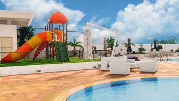 Relax by the pool surrounded by palm trees and lounge chairs.
