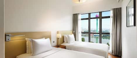 Habitación de hotel con dos camas, una ventana con vista a la ciudad, una lámpara y un aplique.