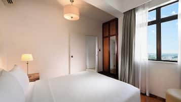 A hotel room with a bed, a nightstand, a lamp, a window with curtains, and a view of the city.