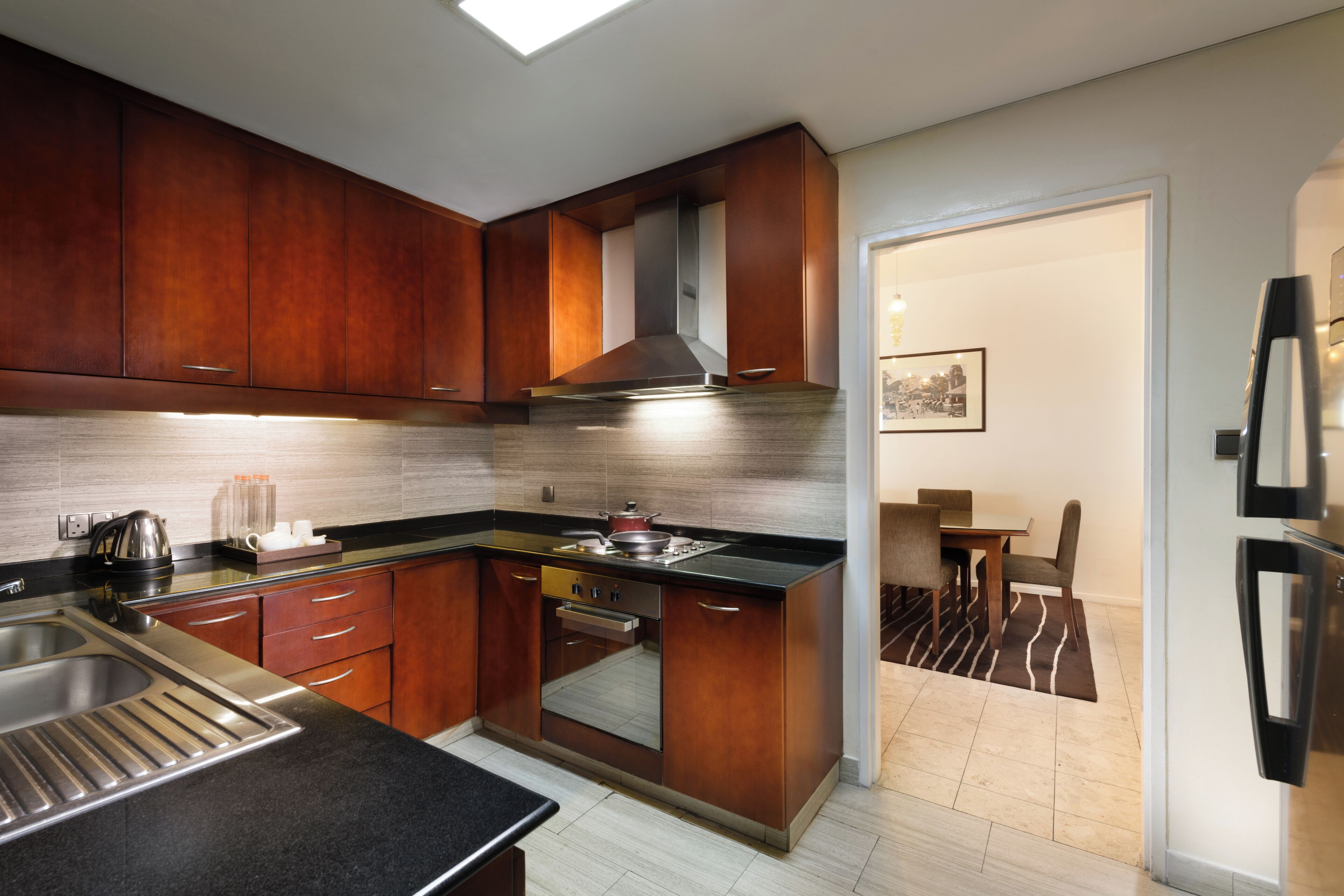 Una cocina moderna con armarios de madera, un lavamanos de acero inoxidable y un horno empotrado.