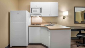 A compact kitchen with a refrigerator, microwave, sink, and a small dining area.