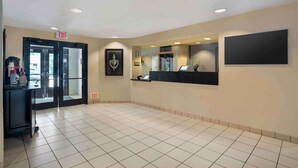 A hotel lobby with a reception desk, an exit sign, and a framed picture on the wall.